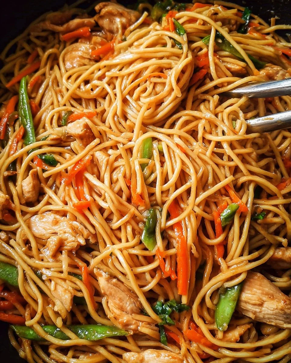 Delicious homemade chicken lo mein served in a bowl with colorful vegetables.